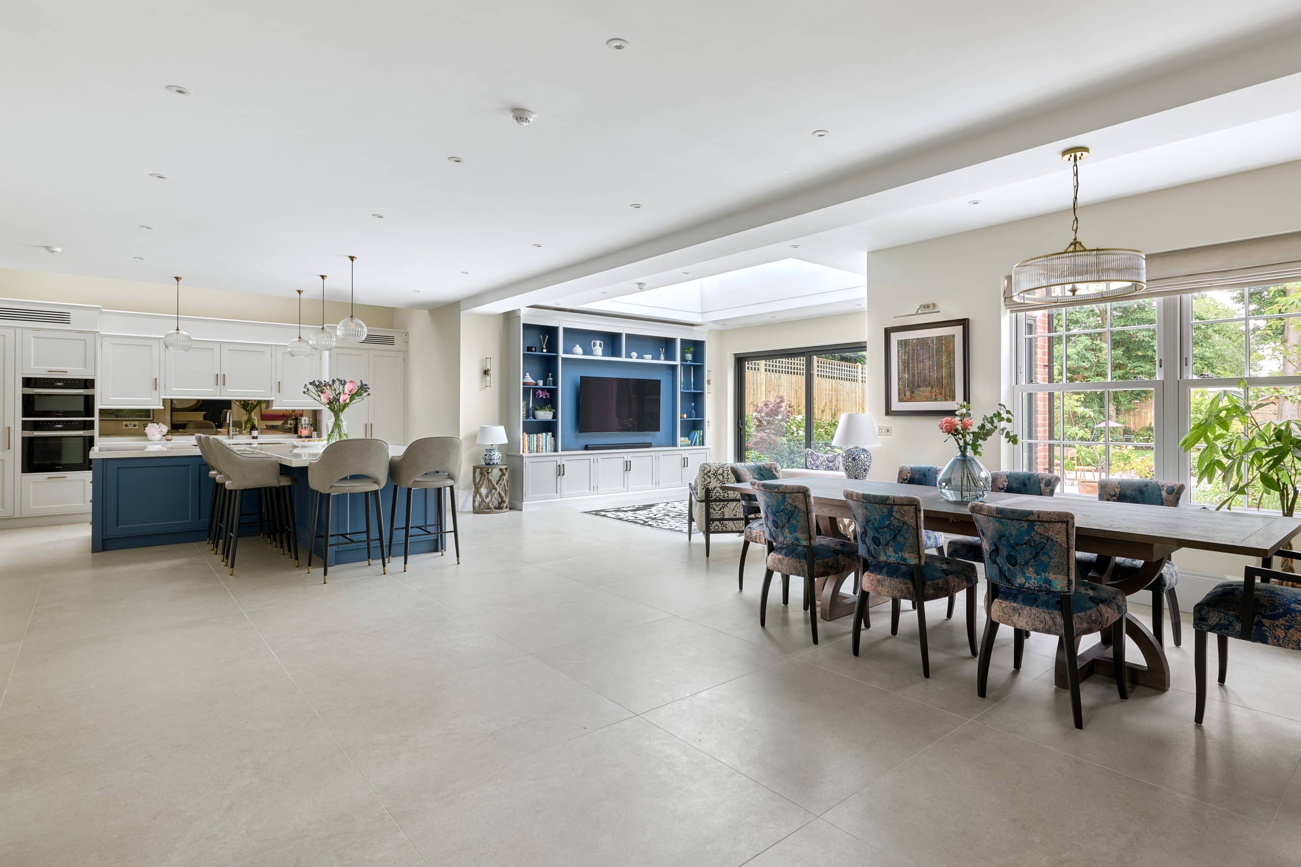 Open plan kitchen layout with blue hand painted kitchen island and tv media wall.